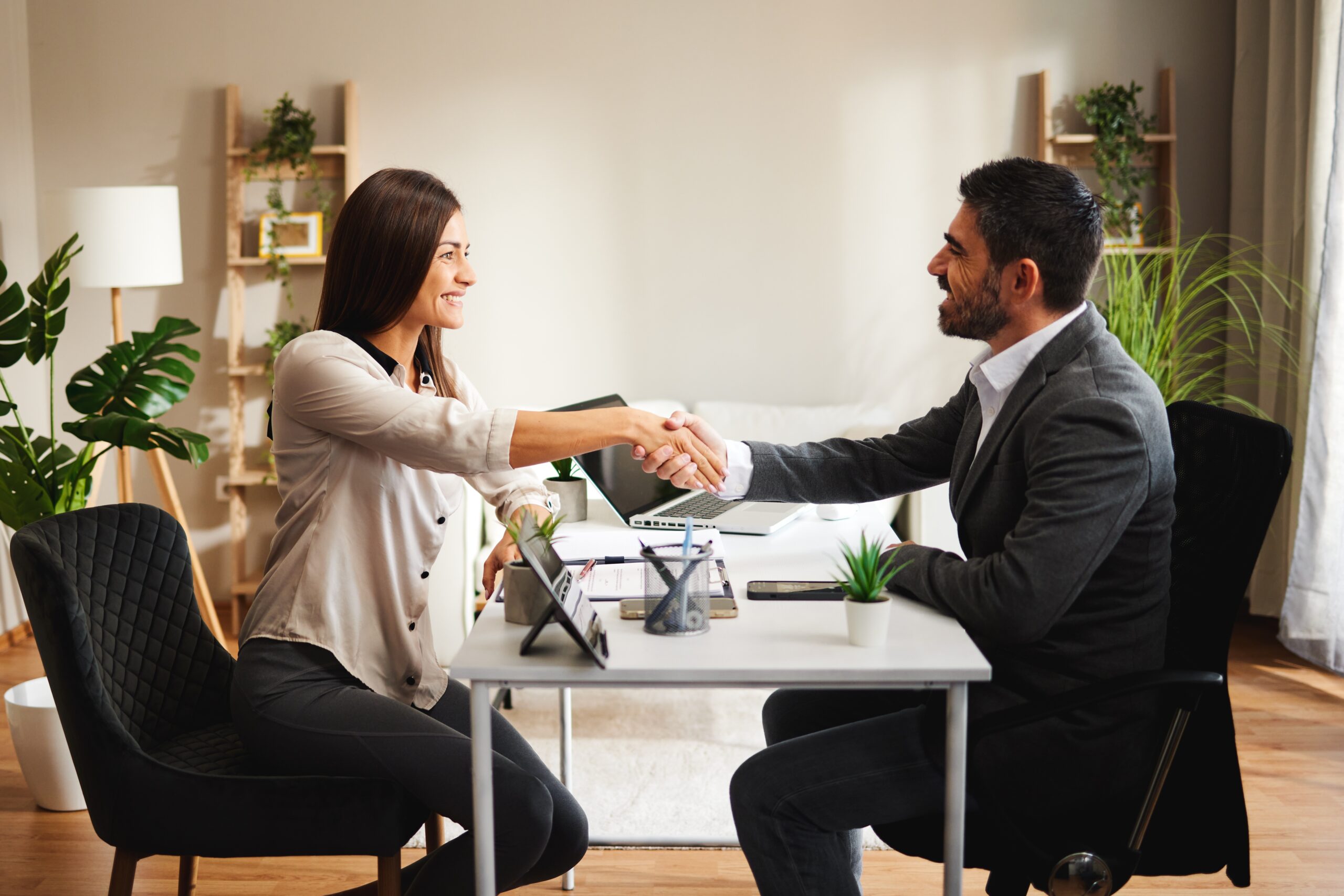 Two people shaking hands in an office, with text boxes displaying a conversation about completing and checking a bookkeeping setup.